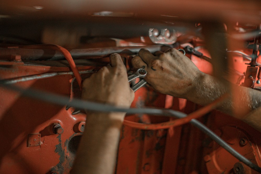 Manos revisando el escape bajo un auto